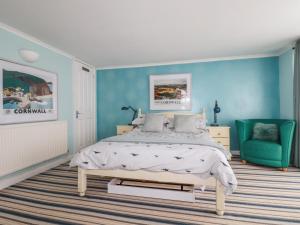 Un dormitorio con una cama y una pared azul. en Blue Bay Beach House, en Newquay