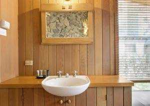 a bathroom with a white sink and a stone wall at Seadog in Dinner Plain +8 photos