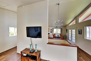 a living room with a flat screen tv on a wall at Big Island Getaway, Ocean View Paradise in Ninole