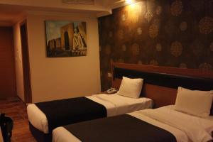 a hotel room with two beds and a painting on the wall at Merci Hotel Erbil in Erbil