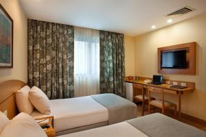 a hotel room with two beds and a desk at Windsor Martinique Copacabana in Rio de Janeiro +37 photos