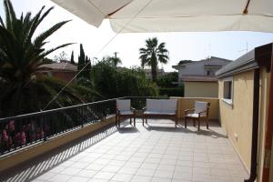 a balcony with two chairs and an umbrella at La Villa di Uccio in Marina di Modica