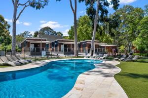 uma piscina em frente a uma casa com árvores em Levi Adelaide Holiday Park em Adelaide