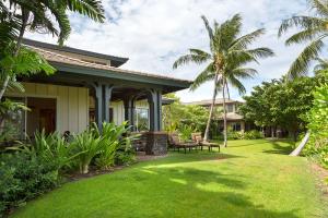 una casa con un patio con césped verde y palmeras en Mauna Lani 2002, en Waikoloa