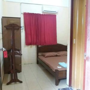 盧穆特的住宿－KAMILA MOTEL TELUK SENANGIN，小房间,配有一张带红色窗帘的床