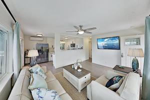 a living room with two couches and a flat screen tv at Nahenahe Cottage in Wailea