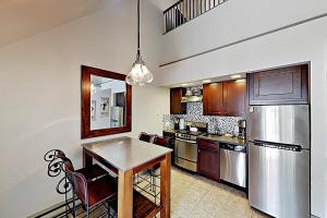 a kitchen with a table and a stainless steel refrigerator at Lodge at Mountain Village #306 in Park City