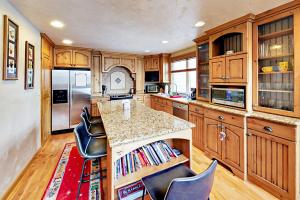 a kitchen with wooden cabinets and a island with chairs at Three Kings Haven 194 in Park City
