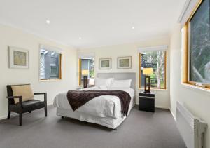 a white bedroom with a bed and a chair at Sun Dew in Dinner Plain