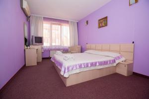 a purple bedroom with a bed and a tv at Семеен Хотел Сокол in Sandanski
