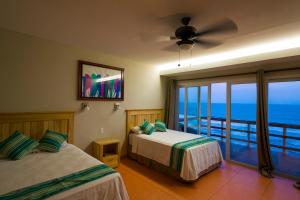 a bedroom with two beds and a view of the ocean at Hotel Los Mangos El Salvador in El Cuco +87 photos