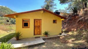 una pequeña casa amarilla con una puerta en un campo en Cabañas Yasmina, en Mazamitla