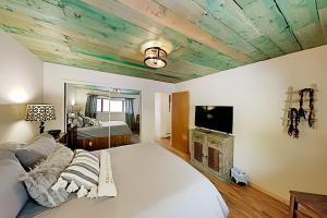a bedroom with a white bed and a tv and a ceiling at Mountain Escape in Taos Ski Valley
