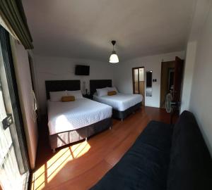 ein Schlafzimmer mit 2 Betten und einem Sofa in einem Zimmer in der Unterkunft Global Airport Inn FREE Shuttle in Guatemala