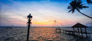 una luz de la calle junto a una playa con una palmera en Kallanchery Retreat, en Ernakulam