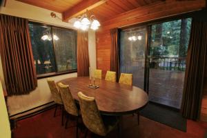 uma sala de jantar com uma mesa de madeira e cadeiras em Snowline Cabin #35 - A pet-friendly country cabin. Now has air conditioning! em Glacier