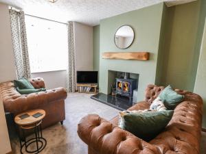 a living room with two leather couches and a fireplace at TurTwig Cottage in Blaenau-Ffestiniog