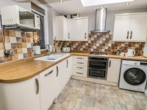 a kitchen with white cabinets and a washer and dryer at TurTwig Cottage in Blaenau-Ffestiniog