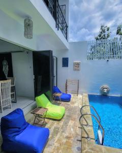 ein Pool mit blauen und grünen Stühlen daneben in der Unterkunft Breezes Villa in Ngingas