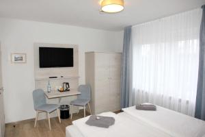 una camera d'albergo con due letti, un tavolo e una televisione di Hotel Pension Norddeich a Norddeich Altre 43 foto