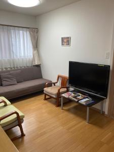 a living room with a flat screen tv and a couch at 森のカフェ in Beppu