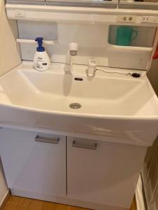 a white bathroom sink with a bottle of soap on it at 森のカフェ in Beppu