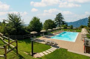 a swimming pool with chairs and umbrellas on a lawn at Hotel Bellavista in San Zeno di Montagna