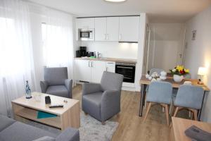 a living room with a table and chairs and a kitchen at Ferienwohnungen Strandglück in Norddeich