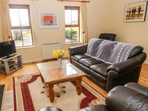 a living room with a leather couch and a coffee table at Kenmare Bay Cottage in Kenmare