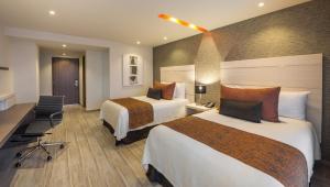 Habitación de hotel con 2 camas y escritorio en Real Inn Celaya, en Celaya