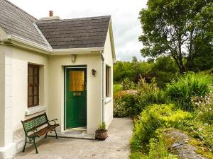 een groene deur op een wit huis met een bank bij Hawthorn Farm Cottage in Curry