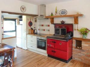 een keuken met rode kasten en een rode kachel bij Hawthorn Farm Cottage in Curry