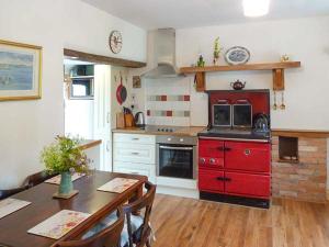een keuken met een tafel en een rode kookplaat bij Hawthorn Farm Cottage in Curry