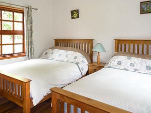 a bedroom with two beds and a window at Hawthorn Farm Cottage in Curry