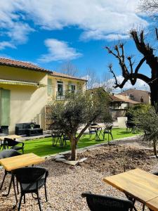 a patio with tables and chairs in a yard at Hotel De Ma Tante in Lamalou-les-Bains