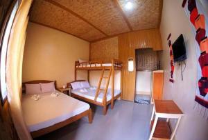 a room with two bunk beds and a tv at Telesfora Beach Cottage in El Nido