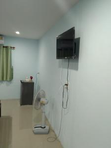 a room with a fan and a tv on a wall at OYO 75400 Moo Yim Resort in Rayong
