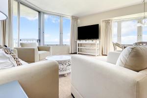 a living room with white furniture and large windows at Golden Arms 111 in New Smyrna Beach