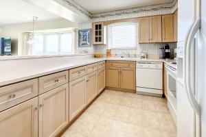 a kitchen with wooden cabinets and white appliances at Golden Arms 111 in New Smyrna Beach