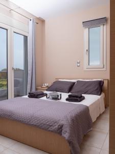 een slaapkamer met een groot bed en 2 ramen bij Villa Stergos in Kremasti