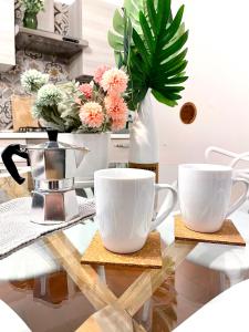 deux tasses de café blanc sur une table en verre avec des fleurs dans l'établissement City Centre Life Apartment Verona, à Vérone