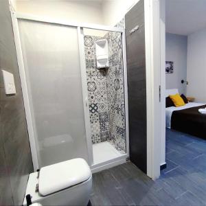 ジャルディーニ・ナクソスにあるPassi di Mare Roomsのバスルーム(シャワー、トイレ付)、ベッド1台が備わります。