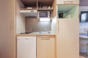 a small kitchen with wooden cabinets and a sink at Belambra Clubs Résidence Le Pradet - Lou Pigno in Le Pradet