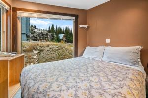 a bedroom with a bed and a large window at Cozy Corner - Whitefoot Lodge 126 in Big White