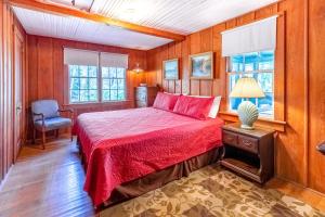 a bedroom with a bed and a chair and windows at Charlotte's Cabin in Waynesville