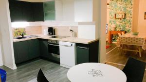 a kitchen with green and white cabinets and a table at Roubaix Gare wifi métro musée calme confort 6 lits - Gite le Ferrum in Roubaix