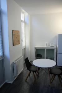 Pokój ze stołem, 2 krzesłami i lodówką w obiekcie Roubaix Gare wifi métro musée calme confort 6 lits - Gite le Ferrum w mieście Roubaix