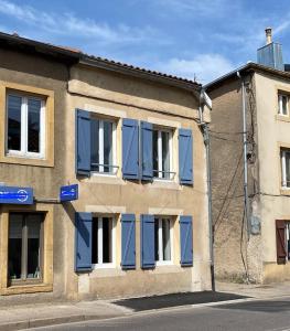um edifício com janelas azuis fechadas numa rua em LE NATUREL em Longeville-lès-Metz