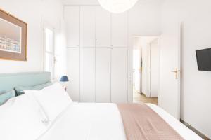 a white bedroom with a bed and a tv at Aeginia 2 in Perdika