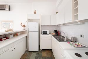 a white kitchen with a refrigerator and a sink at Aeginia 2 in Perdika